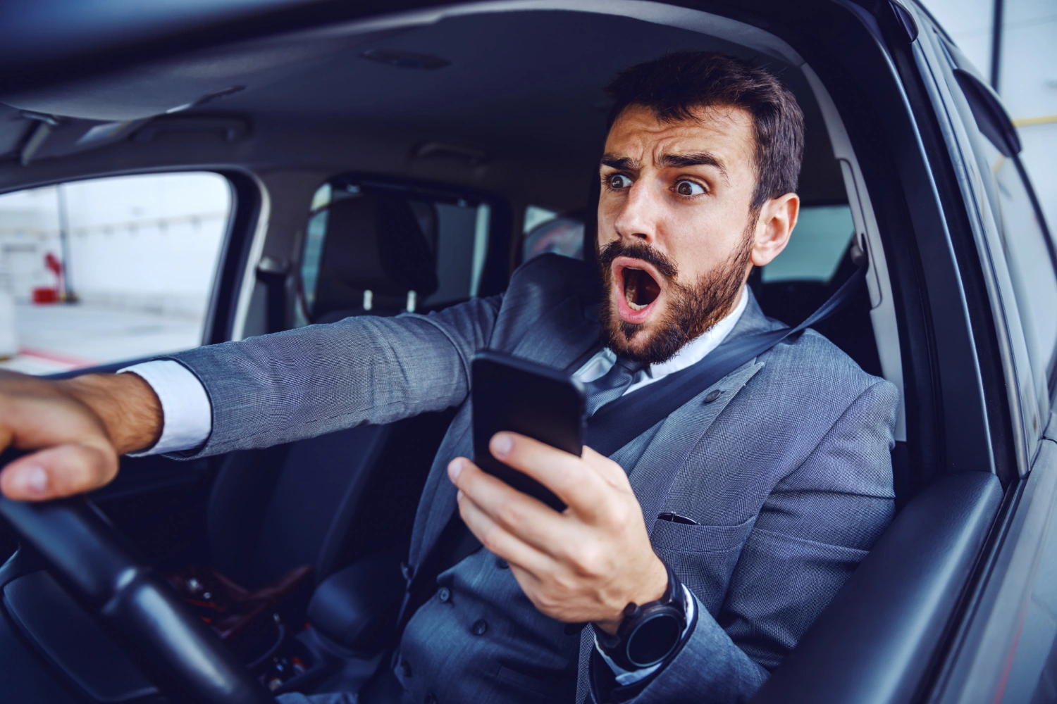 Driver looking shocked while holding a smartphone